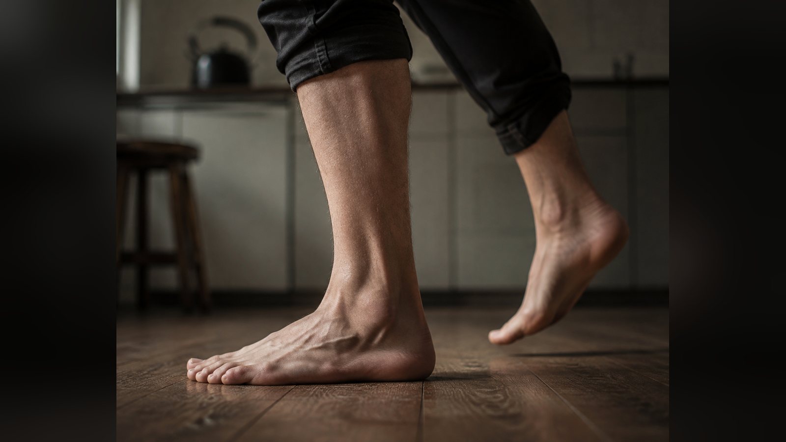 Bare feet stepping heel to toe across a kitchen floor